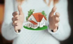 una donna con maglia bianca di cui non si vede il viso tiene tra le mani una casetta 